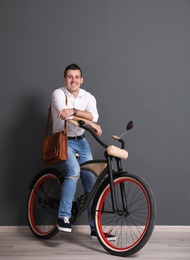 Portrait of handsome young man with bicycle near color wall