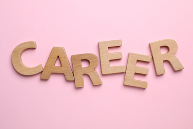 Photo of Word CAREER made with wooden letters on pink background, flat lay