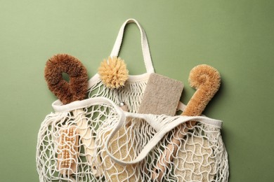 Bag with eco friendly products on green background, flat lay. Conscious consumption