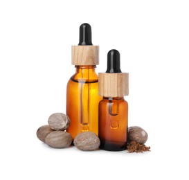 Bottles of nutmeg oil, nuts and powder on white background