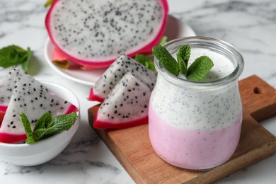 Photo of Tasty pitahaya smoothie, dragon fruits and fresh mint on white marble table