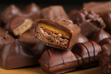 Photo of Many tasty chocolate bars on wooden board, closeup