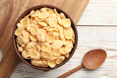 Photo of Bowl of tasty corn flakes and spoon on wooden table, top view