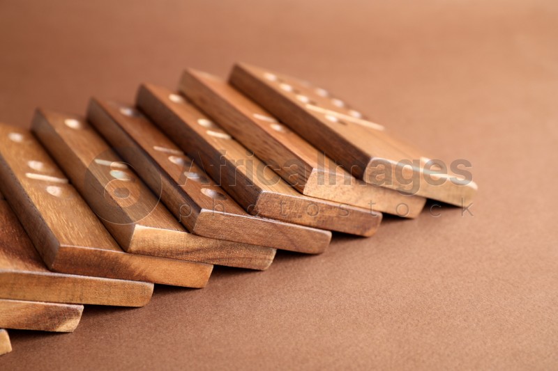 Fallen wooden domino tiles on brown background, closeup