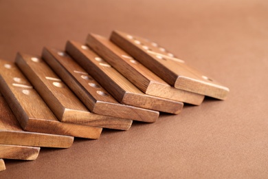 Fallen wooden domino tiles on brown background, closeup