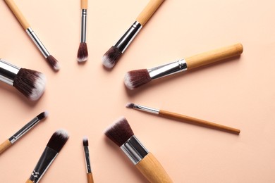 Frame of makeup brushes on beige background, flat lay. Space for text