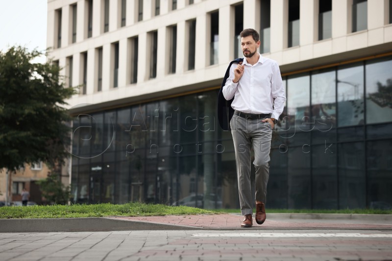 Handsome bearded businessman walking on city street