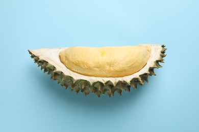 Piece of fresh ripe durian on light blue background, top view
