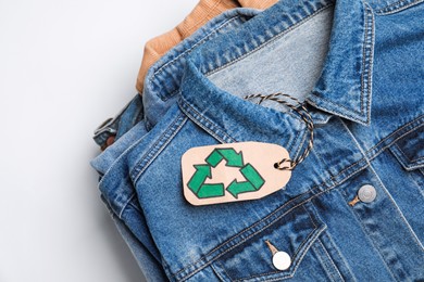 Stack of clothes with recycling label on white background, closeup