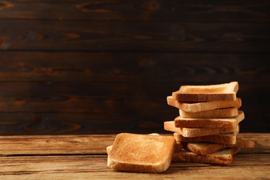 Slices of tasty toasted bread on wooden table, space for text