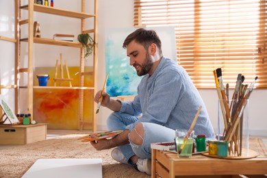 Young man painting with brush in artist studio