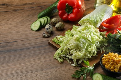 Chinese cabbage and different products on wooden table, space for text