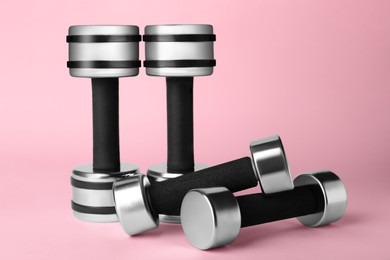 Dumbbells on light pink background. Weight training equipment