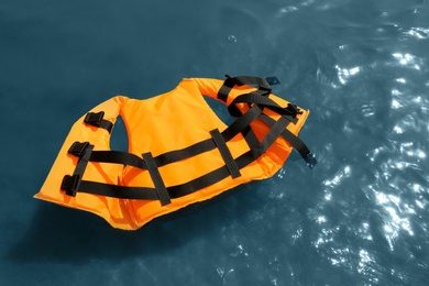 Orange life jacket floating in sea, above view. Emergency rescue equipment