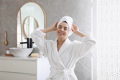 Beautiful young woman wearing soft white robe in bathroom