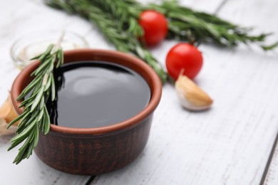 Photo of Organic balsamic vinegar and cooking ingredients on white wooden table, closeup