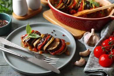 Photo of Delicious ratatouille served with basil on grey wooden table, closeup