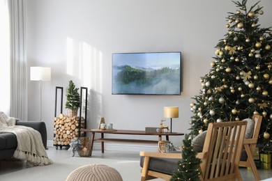 Photo of Modern TV set on light wall in room decorated for Christmas