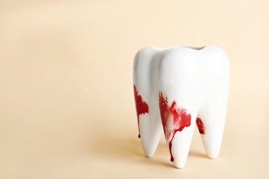 Photo of Tooth model with blood in toothpaste foam on beige background, space for text. Gum problems