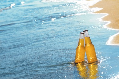 Bottles of cold beer in sea water, space for text