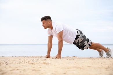 Muscular man doing push up on beach. Body training