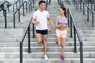 Man and woman in fitness clothes running downstairs outdoors