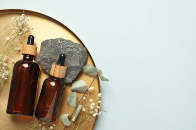 Tray with bottles of face serum, plants and stone on light grey background, top view. Space for text