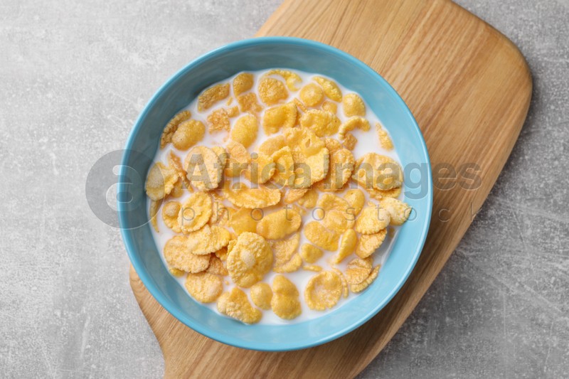 Tasty cornflakes with milk in bowl on light grey table, top view