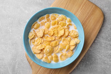 Tasty cornflakes with milk in bowl on light grey table, top view