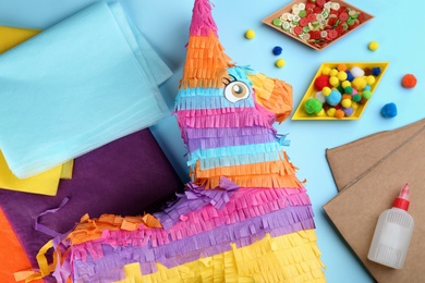 Flat lay composition with cardboard donkey and materials on light blue background. Pinata DIY