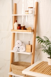 Soft towels and different toiletries on decorative ladder in bathroom. Interior design