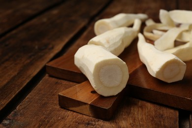 Photo of Whole and cut fresh ripe parsnips on wooden table. Space for text