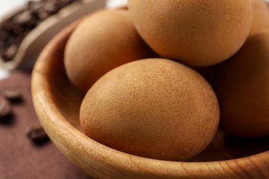 Photo of Easter eggs painted with natural dye in wooden bowl, closeup