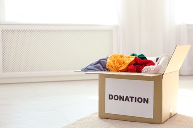 Carton box with donations on floor indoors. Space for text