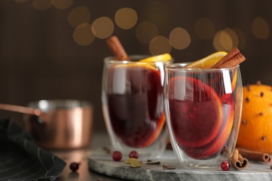 Glasses of tasty mulled wine on table against festive lights