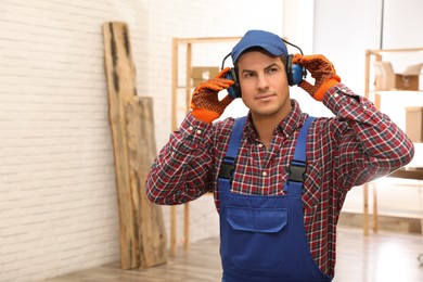 Worker wearing safety headphones indoors, space for text. Hearing protection device