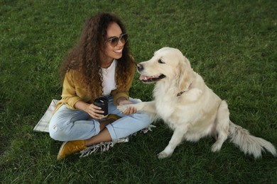 Young African-American woman and her Golden Retriever dog on green grass