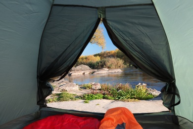 Camping tent with sleeping bags in wilderness, view from inside