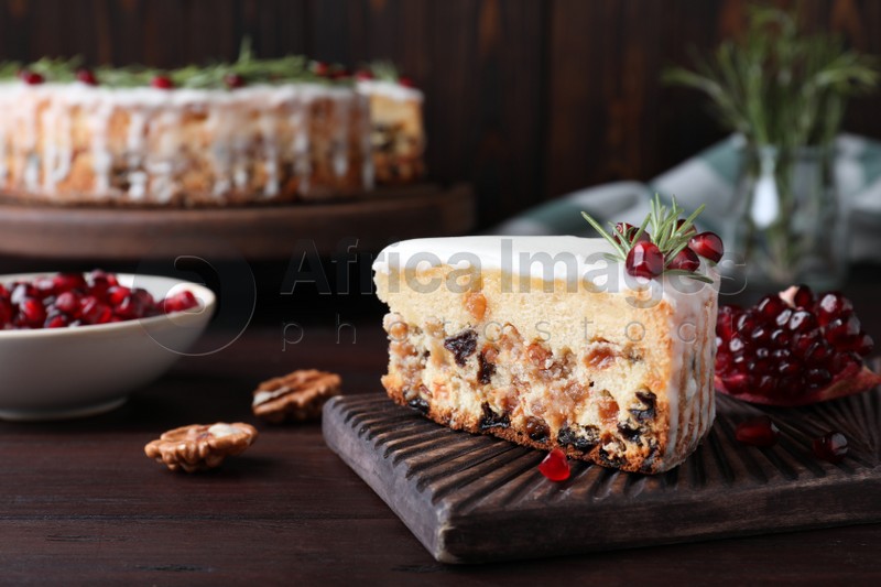 Photo of Piece of traditional homemade Christmas cake and ingredients on wooden table, closeup