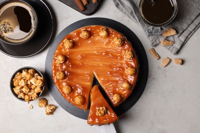 Sliced delicious caramel cheesecake with popcorn served on light grey table, flat lay