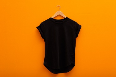 Hanger with blank t-shirt on color background. Mockup for design