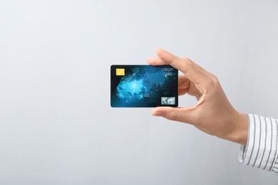 Woman holding credit card on light background