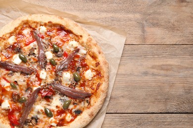 Photo of Tasty pizza with anchovies and olives on wooden table, top view. Space for text