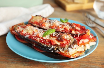 Photo of Baked eggplant with tomatoes, cheese and basil on wooden table, closeup