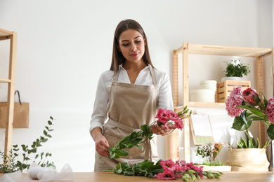 Florist making beautiful bouquet at table in workshop