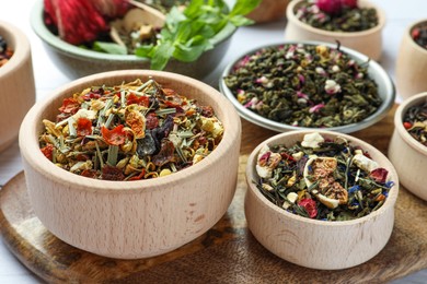 Many different herbal teas in bowls on table, closeup
