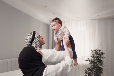 Happy Muslim family with little son in bedroom