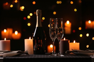 Romantic dinner table setting with burning candles and festive lights