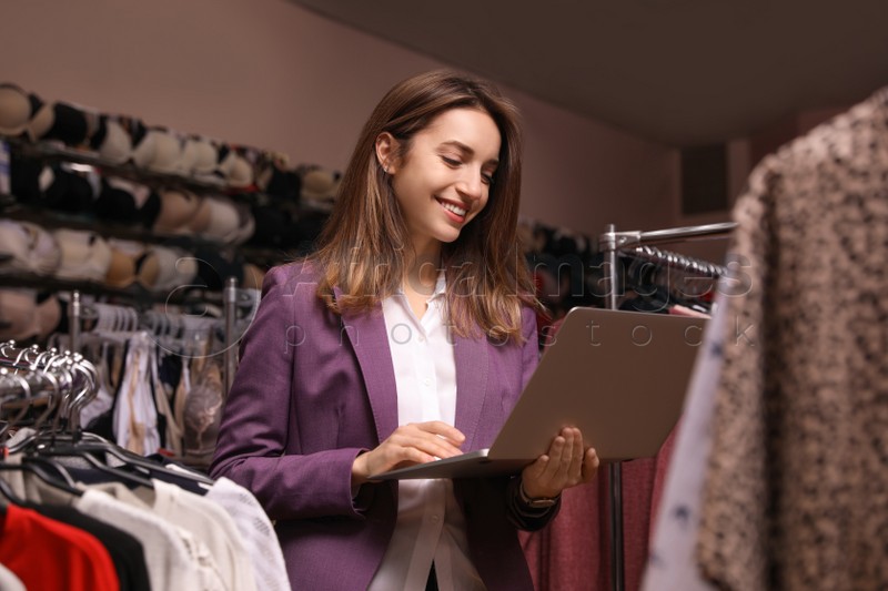 Young business owner with laptop in boutique