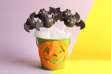 Delicious bat shaped cake pops on color background. Halloween treat